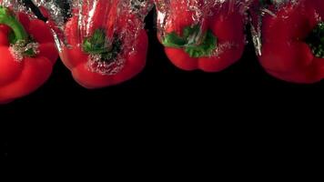 Super slow motion red sweet peppers fall under the water with air bubbles. Filmed on a high-speed camera at 1000 fps.On a black background. video