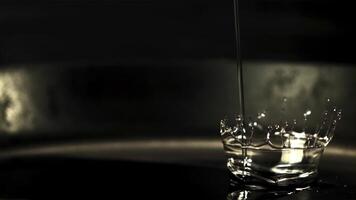 Super slow motion jet oil falls on the pan with splashes. On a black background. Filmed at 1000 fps. video