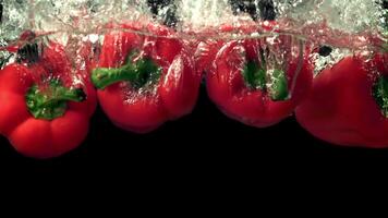 Super slow motion red bell pepper drops water with splashes. Filmed at 1000 fps.On a black background. video