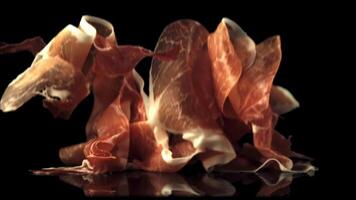 Super slow motion pieces of fragrant Spanish ham fall on the table.Filmed on a high-speed camera at 1000 fps. On a black background. video