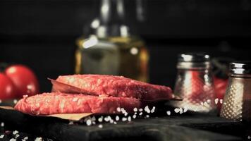 Super slow motion raw burger falls on a cutting board with salt. On a black background.Filmed on a high-speed camera at 1000 fps. video