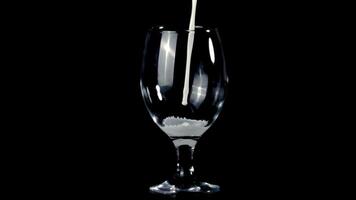 super lento movimento latte versa in il bicchiere su il tavolo. su un' nero sfondo. girato su un' alta velocità telecamera a 1000 fps. video