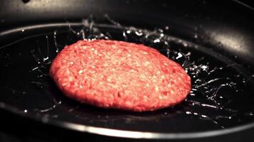 Super slow motion on the pan falls a raw burger with a splash of butter. On a black background. Filmed on a high-speed camera at 1000 fps. video