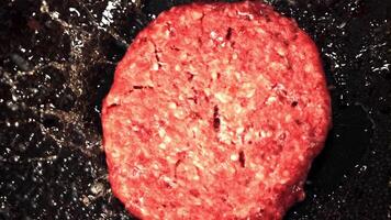 The super slow motion raw burger falls on the pan with a splash of oil. Top view. Filmed at 1000 fps.On a black background. video