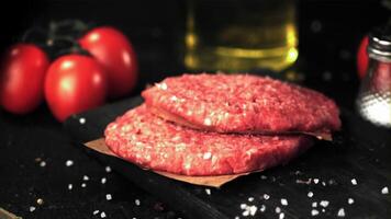 The super slow motion of the raw burger falls on the cutting board. Filmed at 1000 fps.On a black background. video