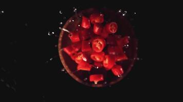 Super slow motion the pieces of chilli in a wooden plate with splashes of water. On a black background.Filmed on a high-speed camera at 1000 fps. High quality FullHD footage video