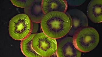 super langzaam beweging kiwi stukken met druppels van water. Aan een zwart achtergrond. gefilmd Aan een hoge snelheid camera Bij 1000 fps. hoog kwaliteit full HD beeldmateriaal video