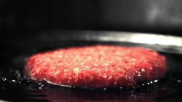 Super slow moving raw burger is fried with oil splashes and hot steam. Filmed at 1000 fps.On a black background. video