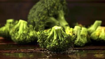 super lento movimento broccoli cascate su il tavolo. su un' di legno sfondo.filmato su un' alta velocità telecamera a 1000 fps. video