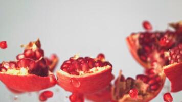 Super slow motion pieces and pomegranate and grains rise up. On a white background. Filmed on a high-speed camera at 1000 fps. High quality FullHD footage video