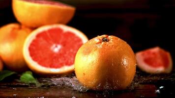 super langzaam beweging vers grapefruit valt Aan de tafel met spatten van water. gefilmd Bij 1000 fps.aan een zwart achtergrond. video