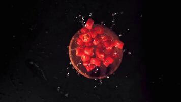 Super slow motion the pieces of chilli in a wooden plate with splashes of water. On a black background.Filmed on a high-speed camera at 1000 fps. High quality FullHD footage video