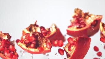 Super slow motion pieces and pomegranate and grains rise up. On a white background. Filmed on a high-speed camera at 1000 fps. High quality FullHD footage video