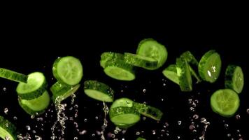 Super slow motion round pieces of cucumber rise with drops of water. On a black background. Filmed on a high-speed camera at 1000 fps. High quality FullHD footage video