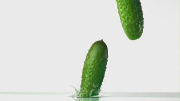 Super slow motion cucumber falls on the water with splashes. On a white background. Filmed on a high-speed camera at 1000 fps. High quality FullHD footage video