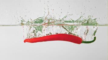 Super slow motion chilli pepper falls into the water with splashes. On a white background.Filmed on a high-speed camera at 1000 fps. High quality FullHD footage video