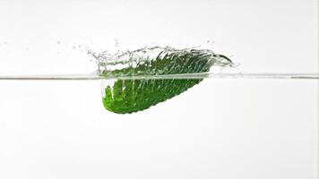 súper lento movimiento Pepino caídas dentro el agua con salpicaduras en un blanco fondo.filmado en un alta velocidad cámara a 1000 fps. alto calidad full HD imágenes video