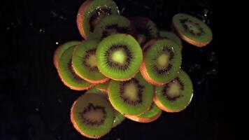 super langzaam beweging kiwi stukken met druppels van water. Aan een zwart achtergrond. gefilmd Aan een hoge snelheid camera Bij 1000 fps. hoog kwaliteit full HD beeldmateriaal video