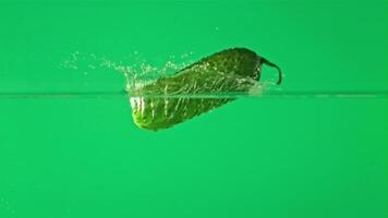 Super slow motion one cucumber falls into water with splashes. On a green background. Filmed on a high-speed camera at 1000 fps. High quality FullHD footage video