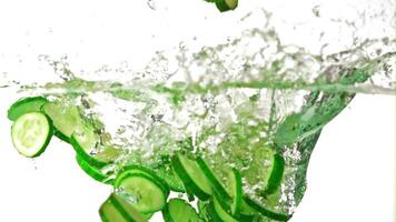 Super slow motion pieces of fresh cucumbers fall into the water with splashes. On a white background.Filmed on a high-speed camera at 1000 fps. High quality FullHD footage video