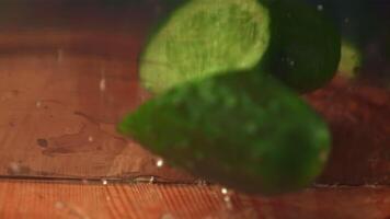 Super slow motion fresh cucumber cut with a knife into two halves. On a wooden background. Filmed on a high-speed camera at 1000 fps. High quality FullHD footage video