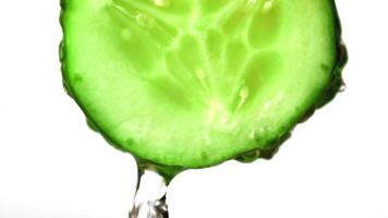 Super slow motion with a piece of cucumber drains water. On a white background. Filmed on a high-speed camera at 1000 fps. High quality FullHD footage video