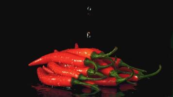 Super slow motion on a bunch of sharp chili peppers drops water. On a black background. Filmed on a high-speed camera at 1000 fps. High quality FullHD footage video