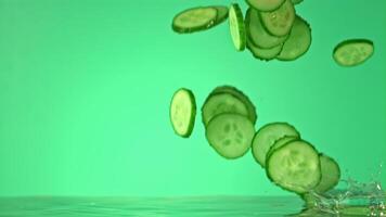 Super slow motion cucumber pieces fall on the water. On a green background. Filmed on a high-speed camera at 1000 fps. High quality FullHD footage video