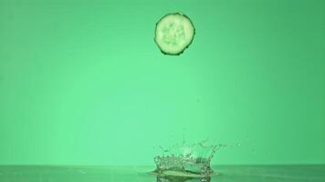 Super slow motion cucumber pieces fall on the water. On a green background. Filmed on a high-speed camera at 1000 fps. High quality FullHD footage video