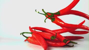 Super slow motion red hot chili pepper falls on the table. On a white background. Filmed on a high-speed camera at 1000 fps. High quality FullHD footage video