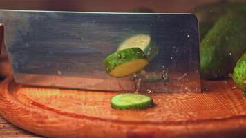 Super slow motion with a large knife cut off the pieces from the cucumber. On a wooden background.Filmed on a high-speed camera at 1000 fps. High quality FullHD footage video