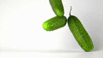 Super slow motion fresh cucumbers fall on the table. On a white background. Filmed on a high-speed camera at 1000 fps. High quality FullHD footage video