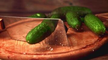 Super slow motion fresh cucumber cut with a knife into two halves. On a wooden background. Filmed on a high-speed camera at 1000 fps. High quality FullHD footage video