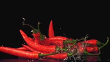 Super slow motion pile of chili pepper pods falls on the table. On a black background. Filmed on a high-speed camera at 1000 fps. High quality FullHD footage video