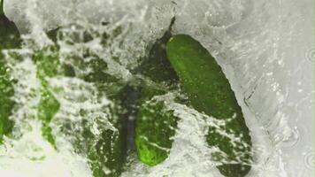 Super slow motion cucumbers fall into the water with splashes. On a white background. Filmed on a high-speed camera at 1000 fps. High quality FullHD footage video