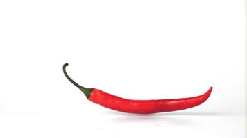 Super slow motion red hot chili pepper falls on the table. On a white background. Filmed on a high-speed camera at 1000 fps. High quality FullHD footage video