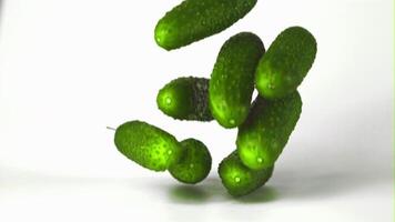 Super slow motion fresh cucumbers fall on the table. On a white background.Filmed on a high-speed camera at 1000 fps. High quality FullHD footage video