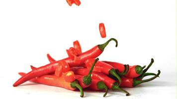 Super slow motion pieces of chili pepper fall on a bunch of pepper pods. On a white background. Filmed on a high-speed camera at 1000 fps.igh quality FullHD footage video