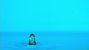 Super slow motion water falls on the table on a blue background. Filmed on a high-speed camera at 1000 fps. High quality FullHD footage video