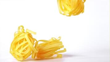 Super slow motion dry pasta tagliatelle falls on table. On a white background.Filmed on a high-speed camera at 1000 fps. High quality FullHD footage video