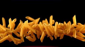 Super slow motion dry penne paste. On a black background. Filmed on a high-speed camera at 1000 fps. High quality FullHD footage video