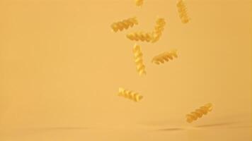 Super slow motion of dry fusilli pasta falls on an orange background. Filmed on a high-speed camera at 1000 fps. High quality FullHD footage video