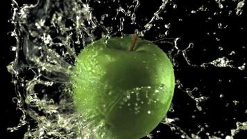 súper lento movimiento agua caídas en el manzana con salpicaduras en un negro antecedentes. filmado en un alta velocidad cámara a 1000 fps video