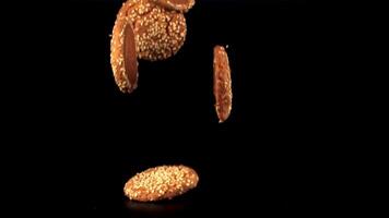 Super slow motion fresh oatmeal cookies with sesame seeds falls on the table. On a black background. Filmed on a high-speed camera at 1000 fps. video