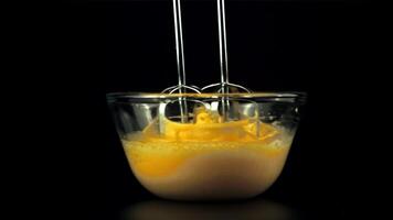 Super slow motion in the transparent bowl is whipped raw eggs with a mixer. On a black background.Filmed on a high-speed camera at 1000 fps. video