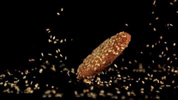 super lento movimento fiocchi d'avena biscotto cascate su il tavolo con sesamo semi. su un' nero sfondo.filmato su un' alta velocità telecamera a 1000 fps. video