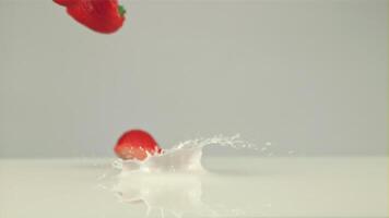 Super schleppend Bewegung geschnitten Erdbeeren Stürze in das Milch mit Spritzer. auf ein Weiß Hintergrund. gefilmt auf ein schnelle Geschwindigkeit Kamera beim 1000 fps video