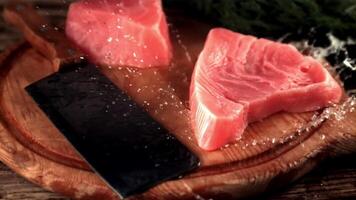 Super slow motion raw tuna steak drops a cutting board with splashes of water. On a wooden background.Filmed on a high-speed camera at 1000 fps. video