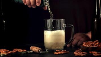 super langzaam beweging de mannetje hand- giet bier in een glas van schuim. Aan een zwart achtergrond. gefilmd Aan een hoge snelheid camera Bij 1000 fps. video