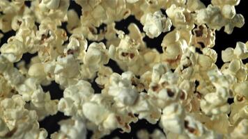 Popcorn flies up and falls down. On a black background. Filmed on a high-speed camera at 1000 fps. High quality FullHD footage video